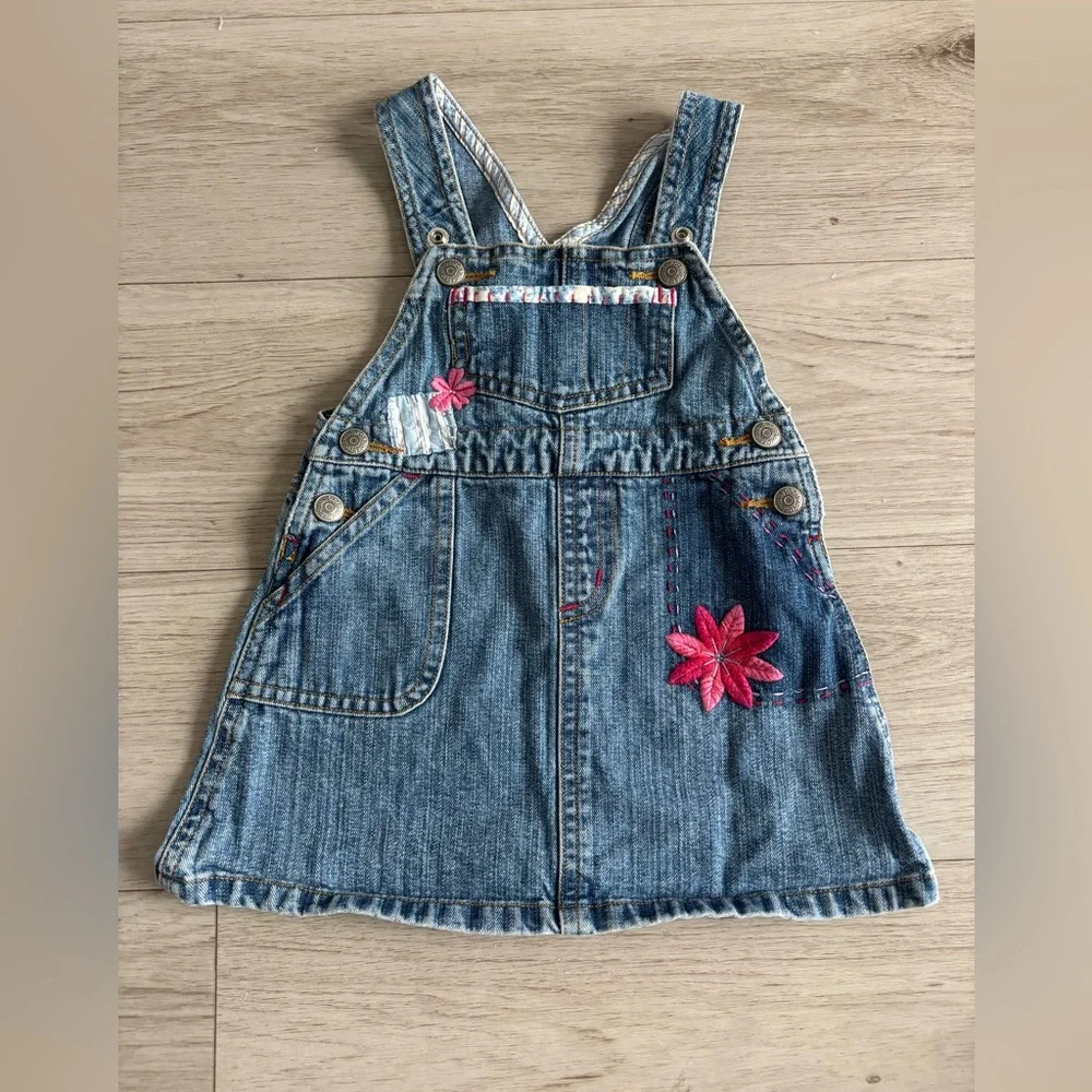 Baby Gap denim jumper dress‎ featuring overall-style straps, embroidered flowers
